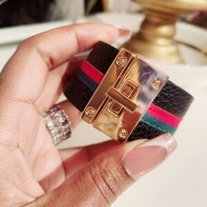 Black faux leather bracelet with green and red trim and gold buckle lock